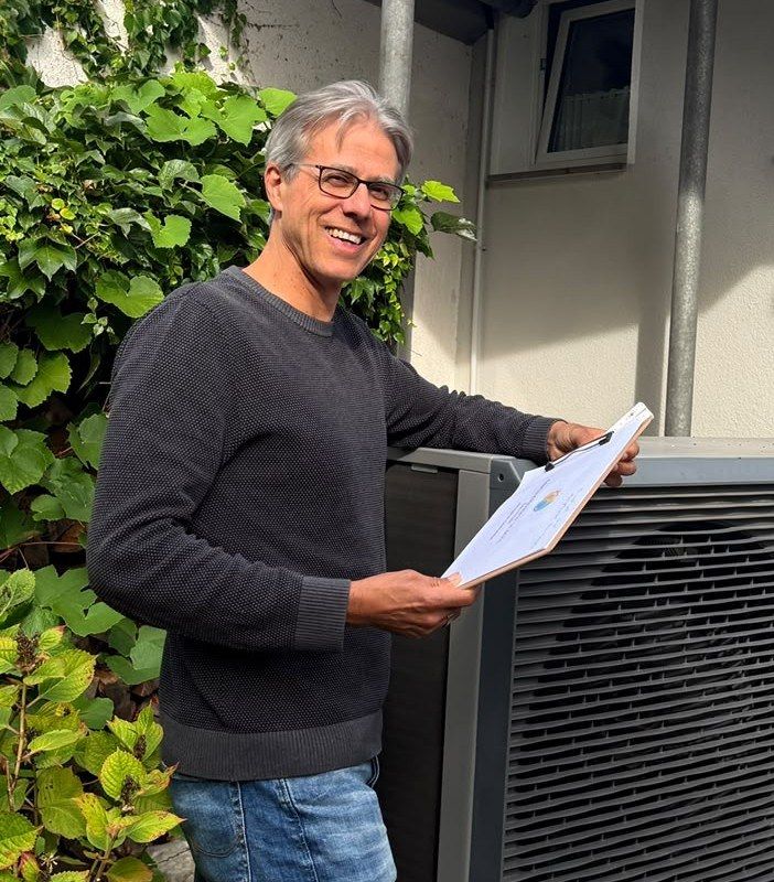 Florian Wardemann, Energieberater in Darmstadt, mit Unterlagen vor einer Wärmepumpe